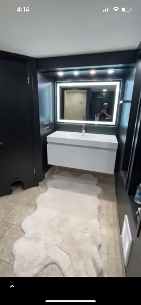 Modern bathroom with floating white vanity, backlit mirror, and a light-colored animal-shaped rug.
