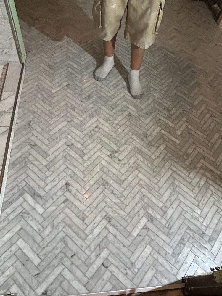 Person stands on a herringbone marble tile floor.