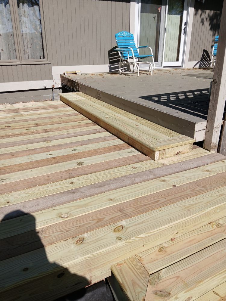 Wooden deck with steps leading up to a higher level, blue chair visible through sliding glass door.