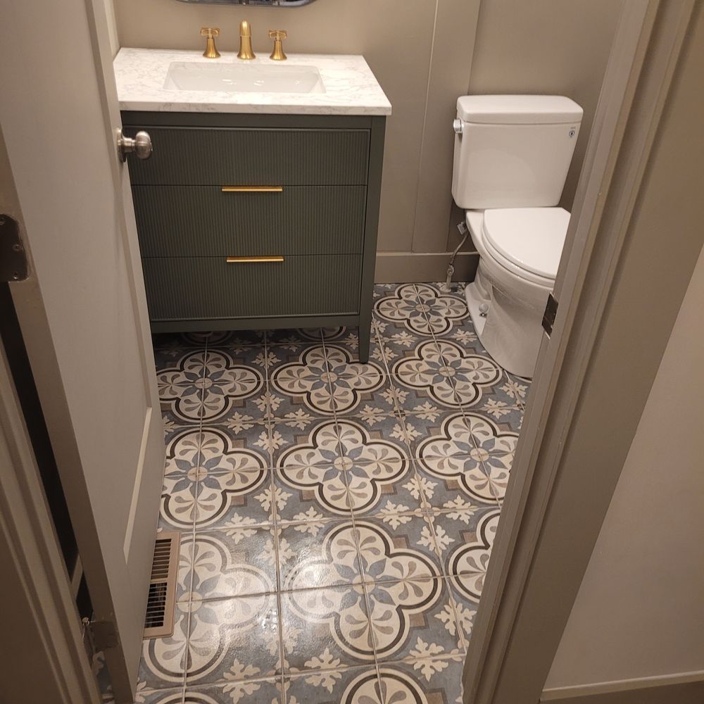 Bathroom with patterned floor, green vanity, white toilet.