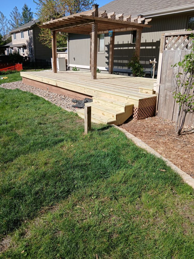 Wooden deck with pergola attached to a house; steps lead down to a grassy backyard.