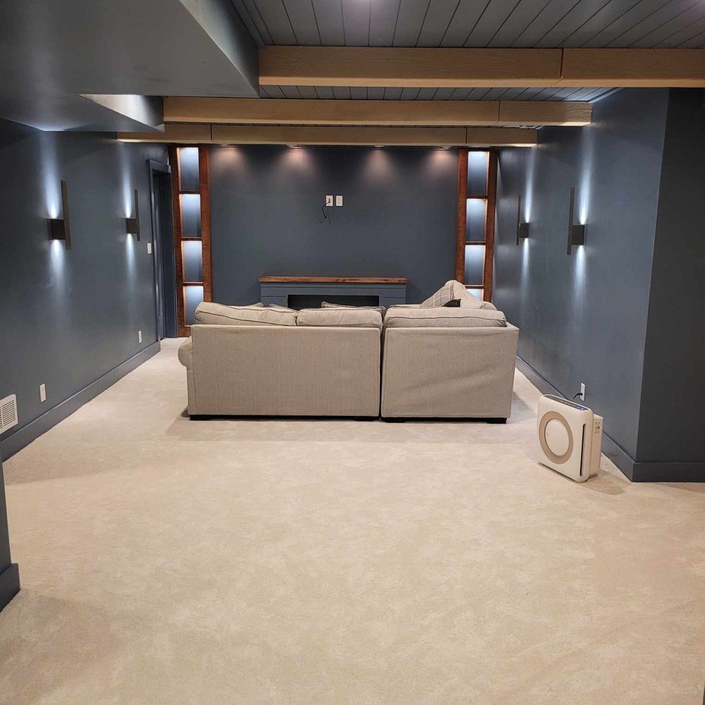 Cozy home theater with gray walls, cream carpet, a gray sectional sofa, and recessed lighting.