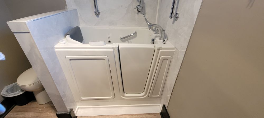 Walk-in bathtub in a bathroom. White tub with a door, chrome shower fixtures, and a toilet.