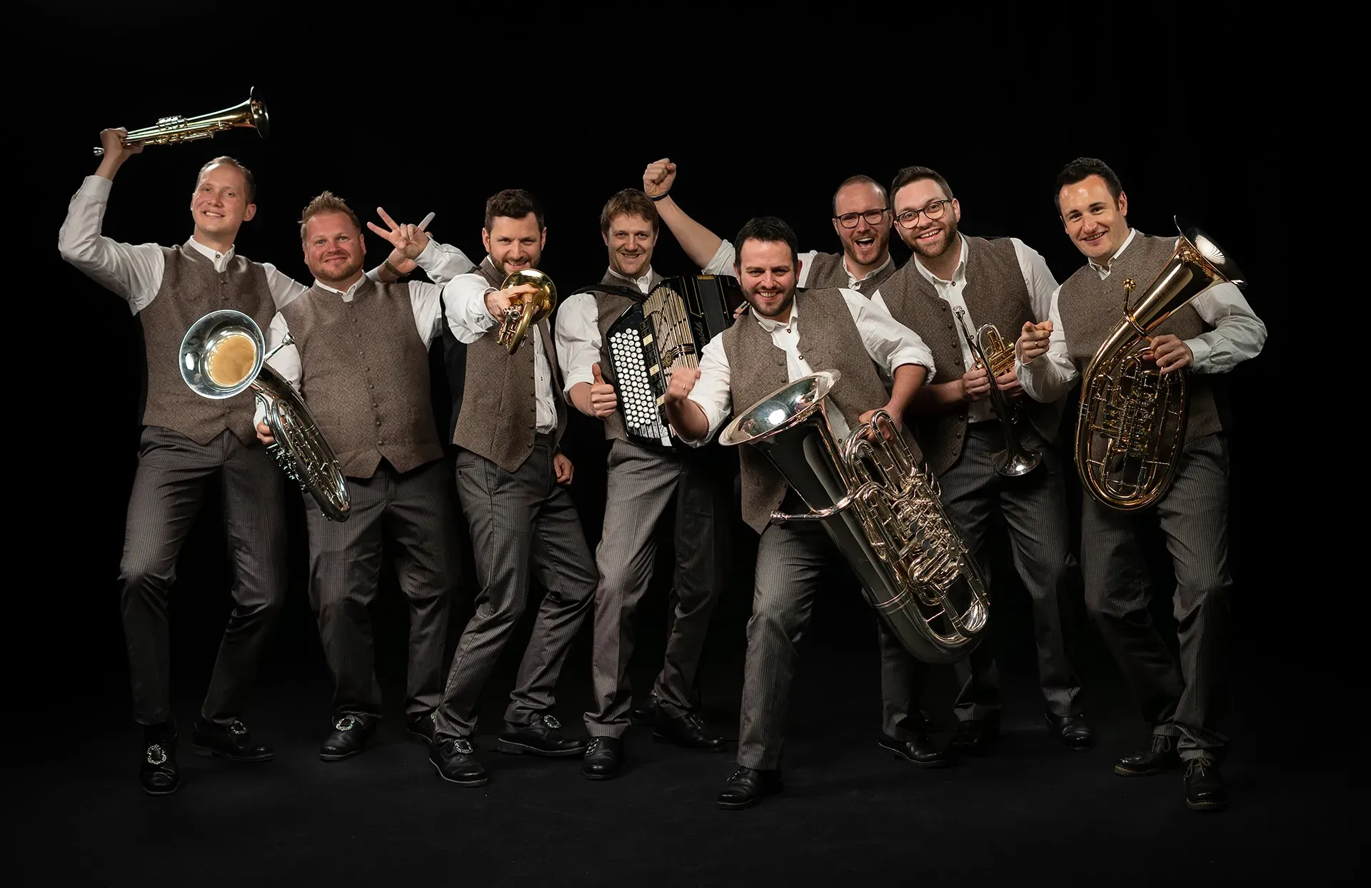 Eine Gruppe von Männern steht mit Blechblasinstrumenten in der Hand nebeneinander.