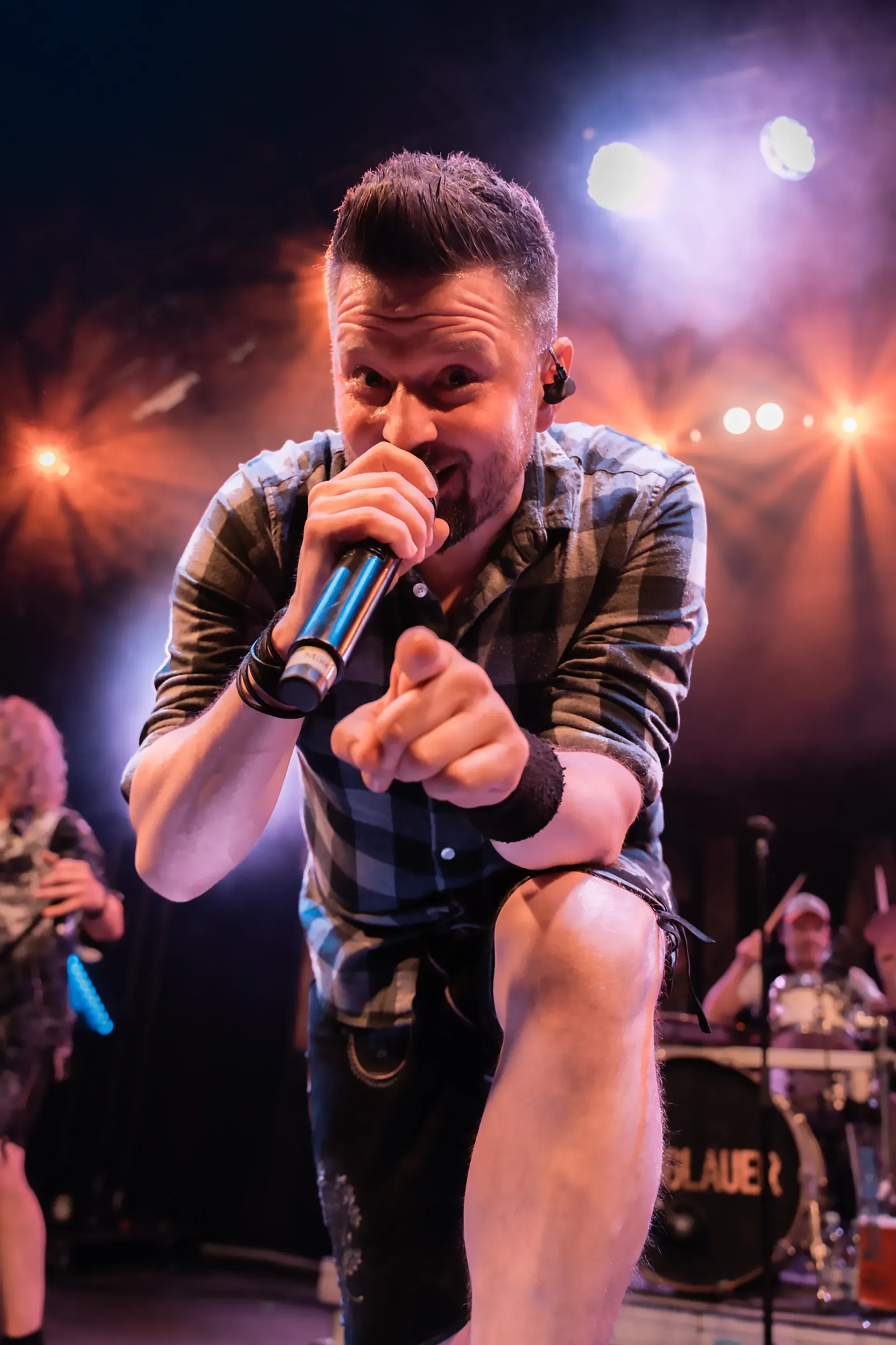 Ein Mann singt auf einer Bühne in ein Mikrofon.