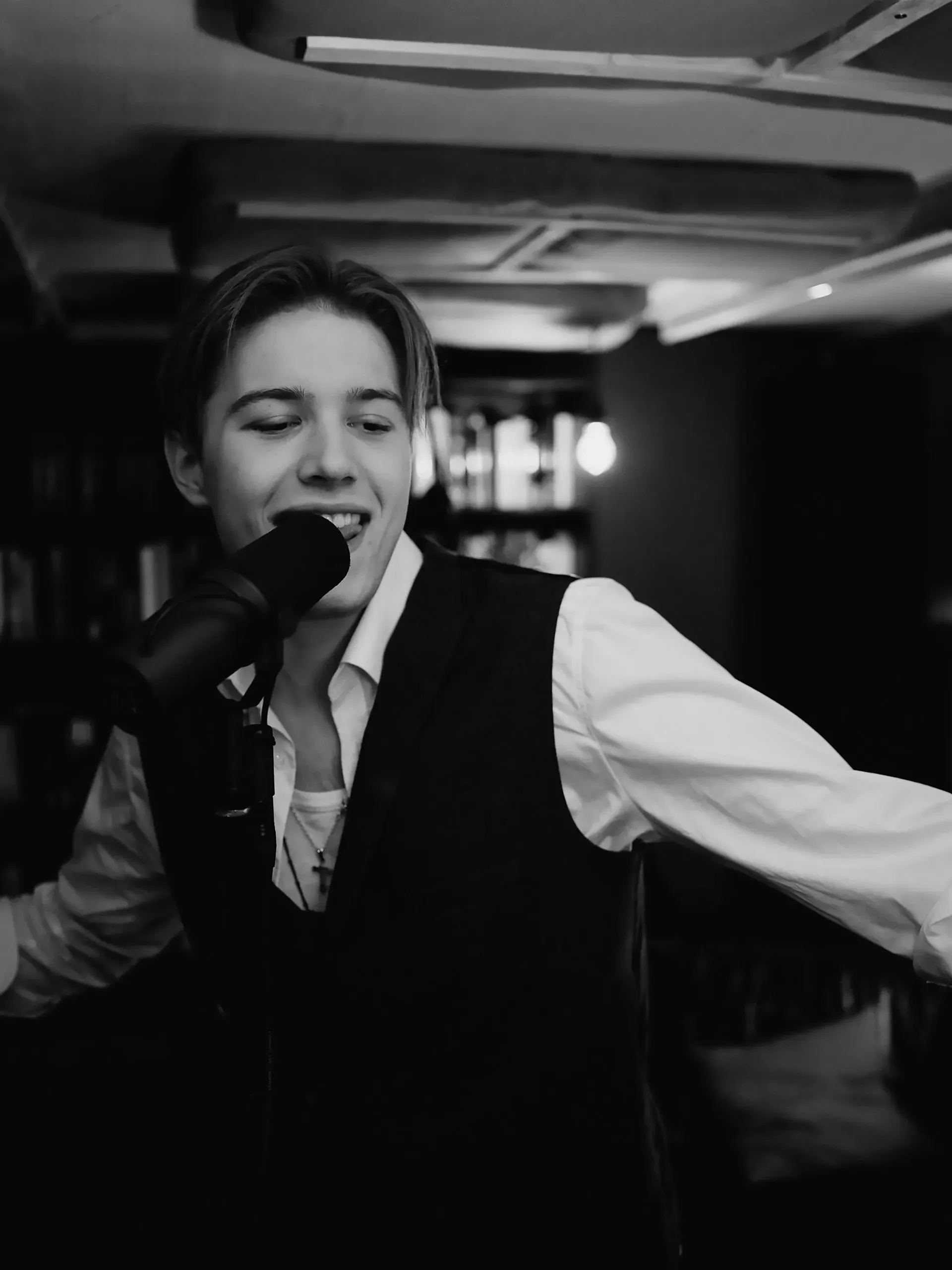 Auf einem Schwarzweißfoto singt ein junger Mann in ein Mikrofon.