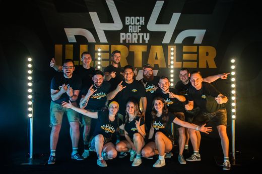 Eine Gruppe von Menschen posiert für ein Foto vor einem Schild mit der Aufschrift „Bock auf Party“