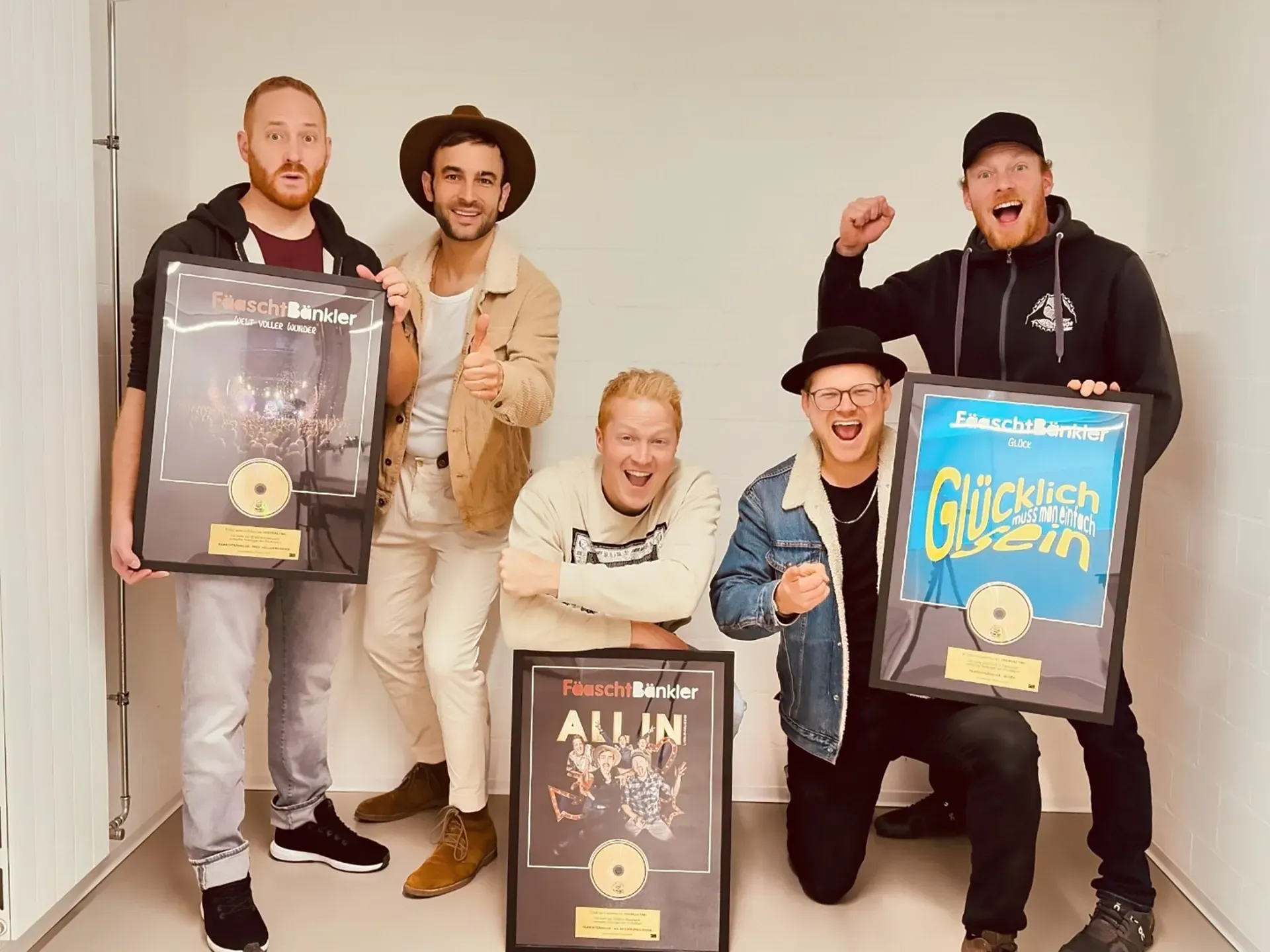 Eine Gruppe von Männern posiert mit mehreren Auszeichnungen in der Hand für ein Foto.