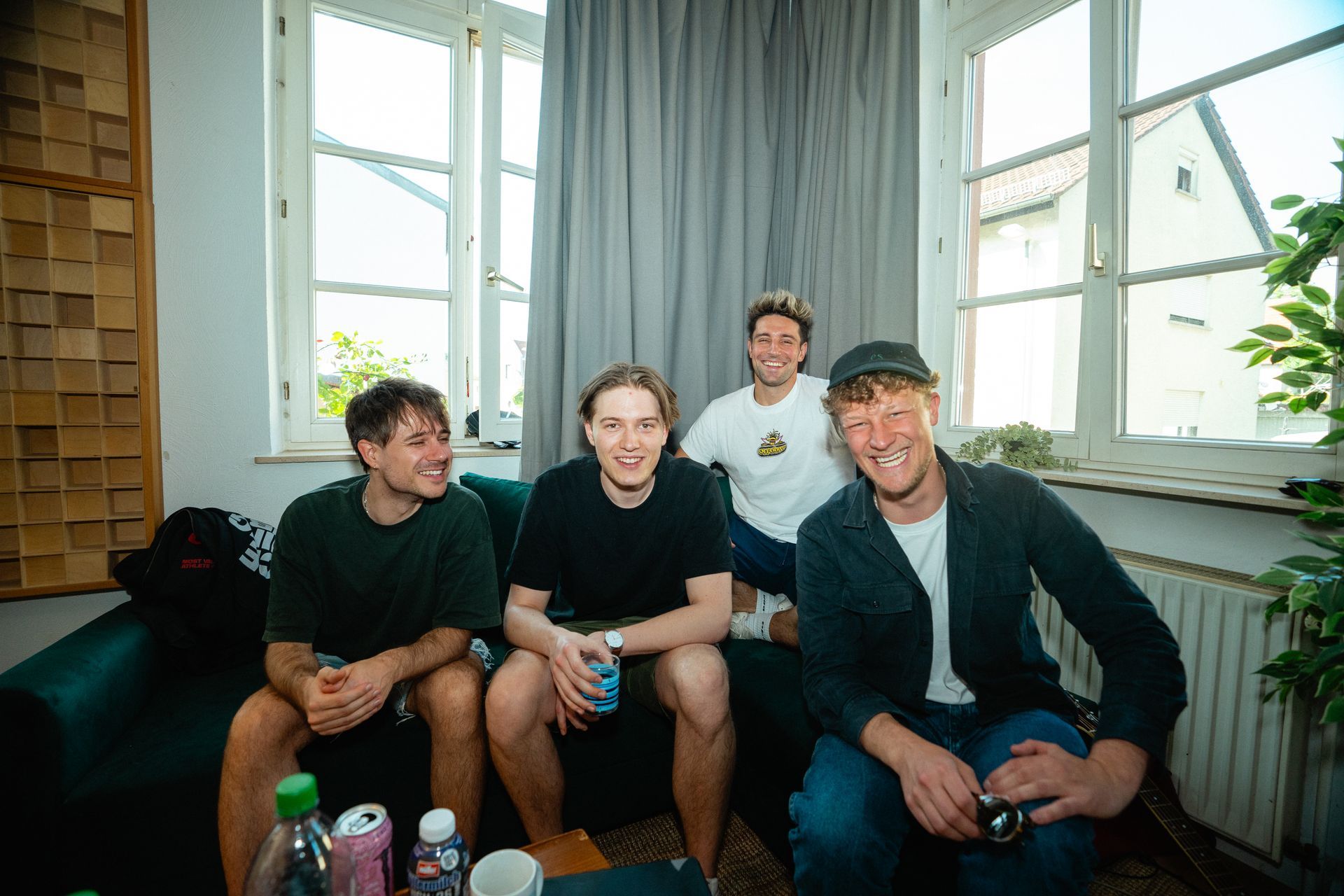 Eine Gruppe junger Künstler:innen sitzen auf einer Couch.