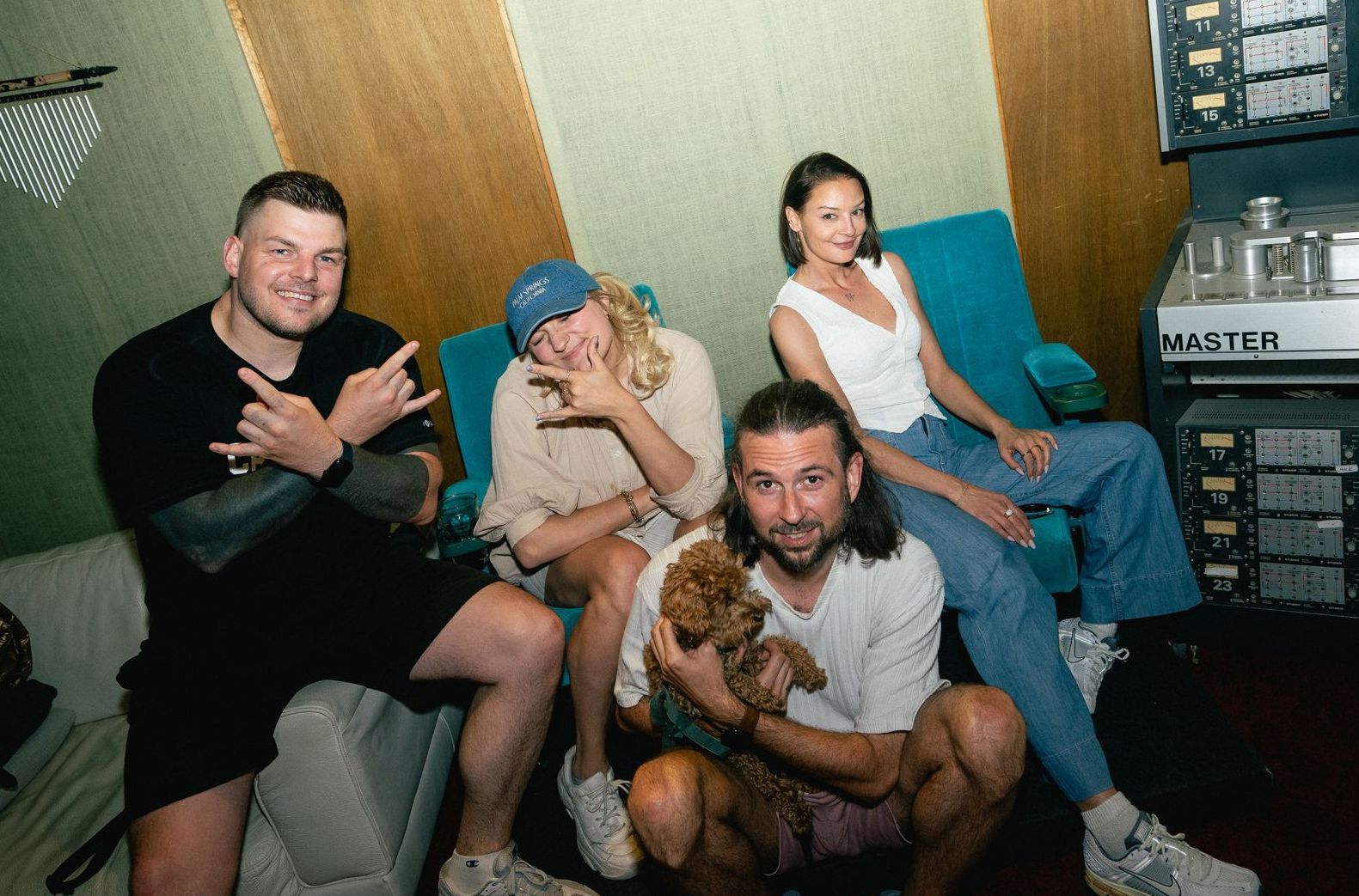 Ein Mann spielt Gitarre, während ein anderer Mann auf ein Mobiltelefon schaut.