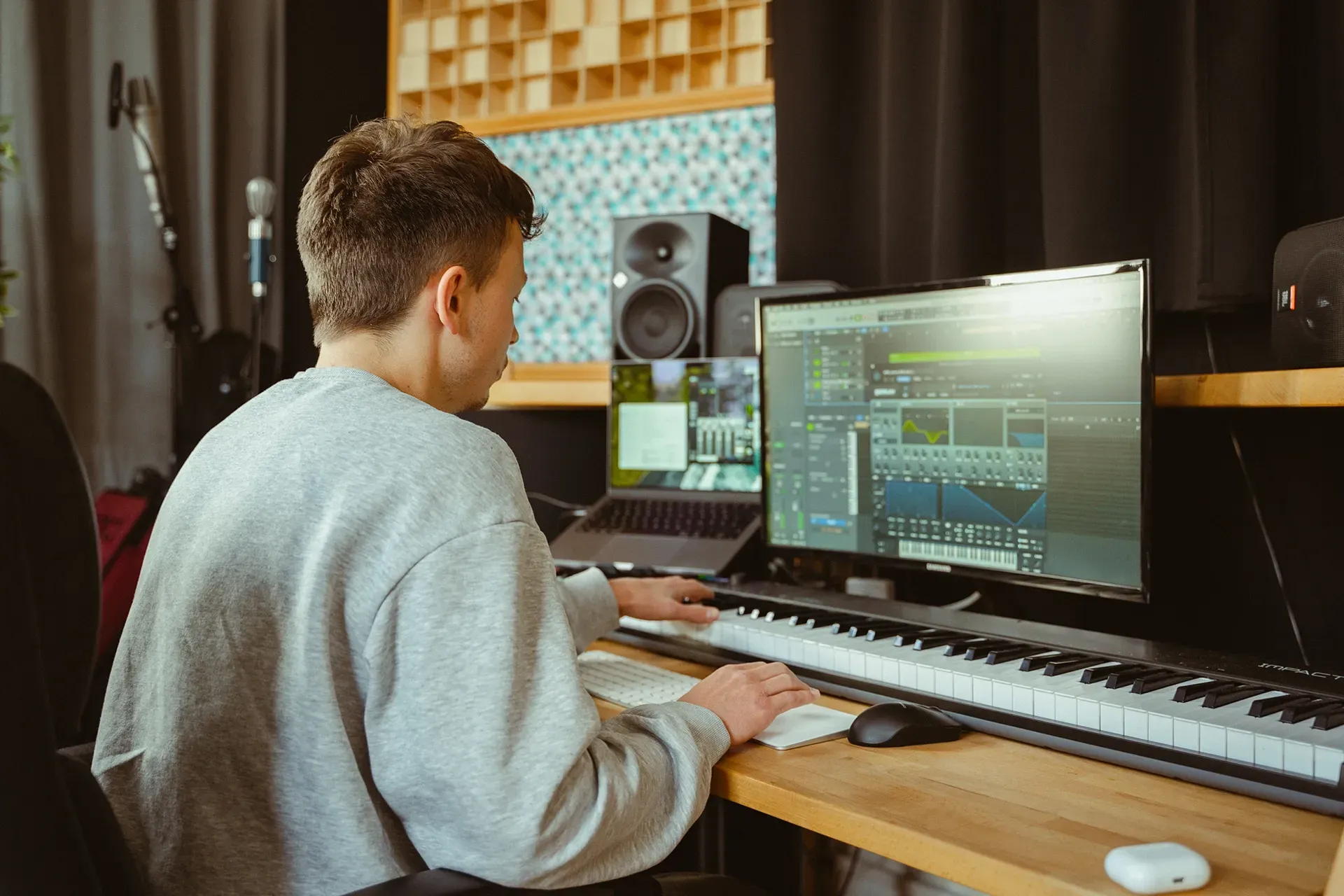 Ein Mann sitzt an einem Schreibtisch vor einem Computer und einer Tastatur.