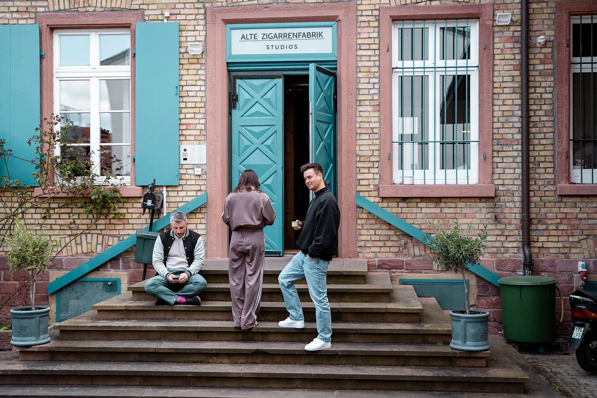 Eine Gruppe von Menschen steht auf den Stufen vor der Eingangstür eines Gebäudes.