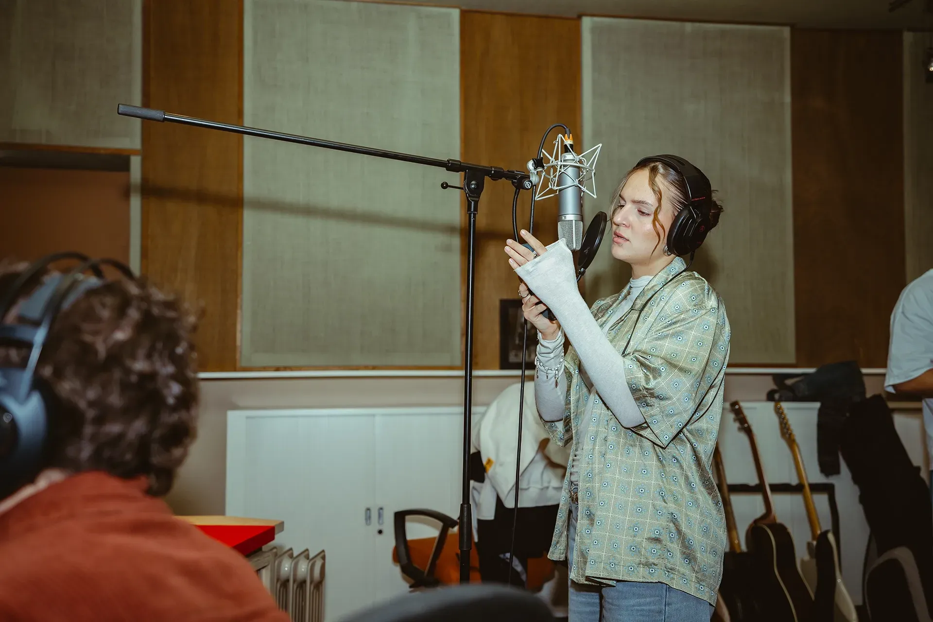 Eine Frau singt in einem Aufnahmestudio in ein Mikrofon.