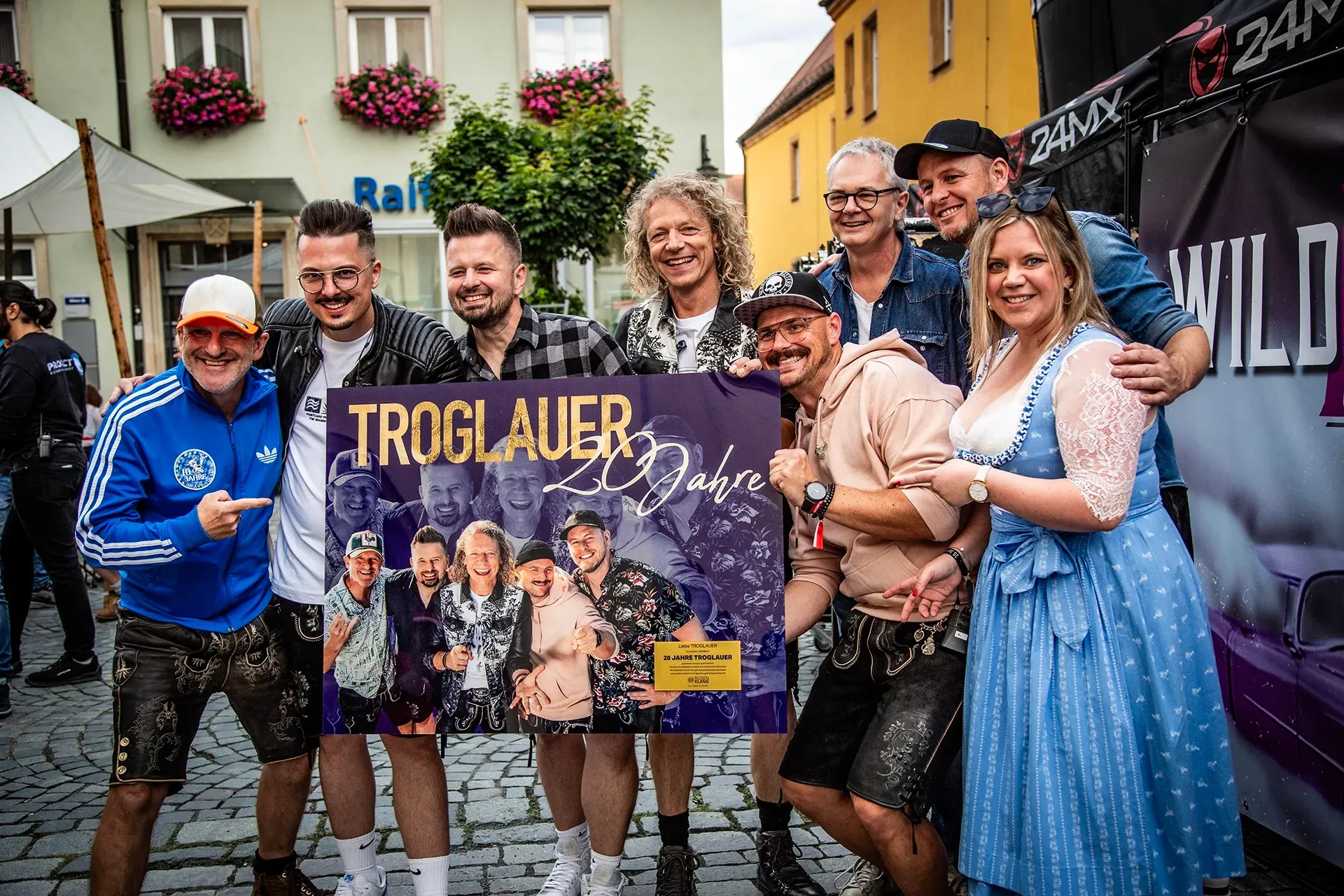 Die Band Troglauer posiert für ein Foto und hält dabei ein Schild hoch.