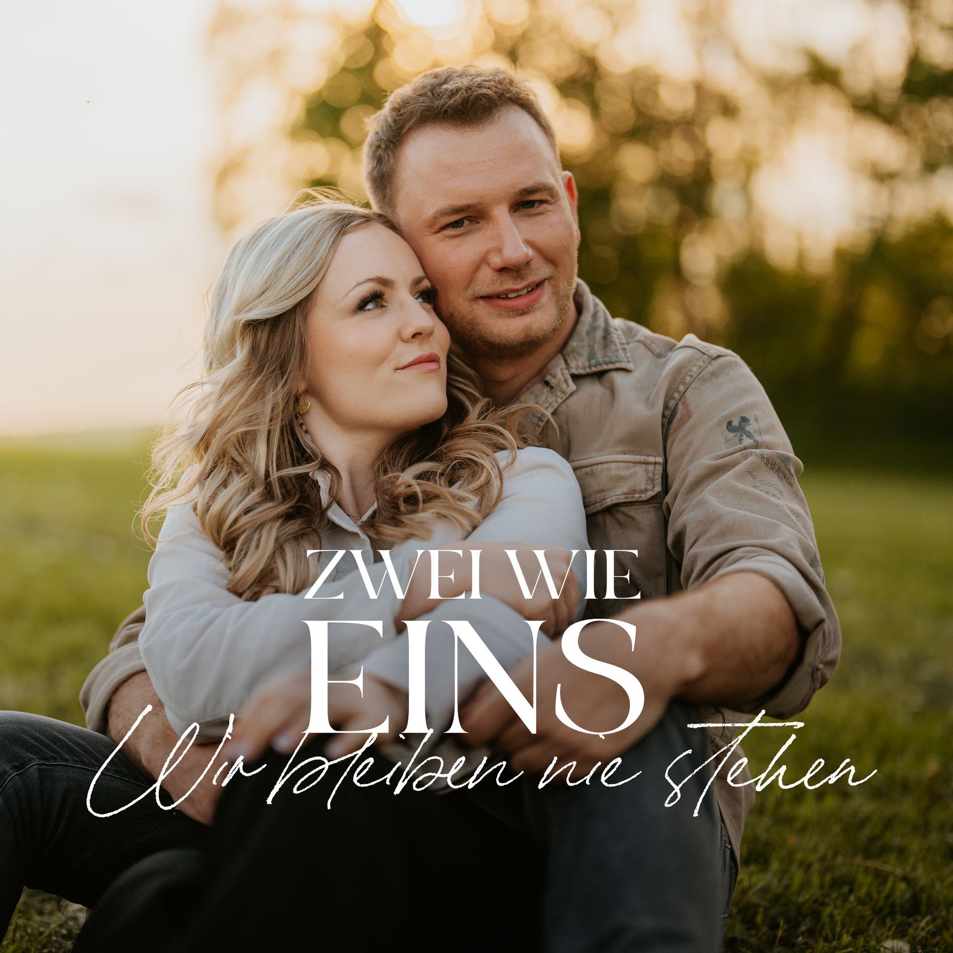 Theres und Philipp Arm in Arm auf einer Wiese sitzend. Das Cover der Single 