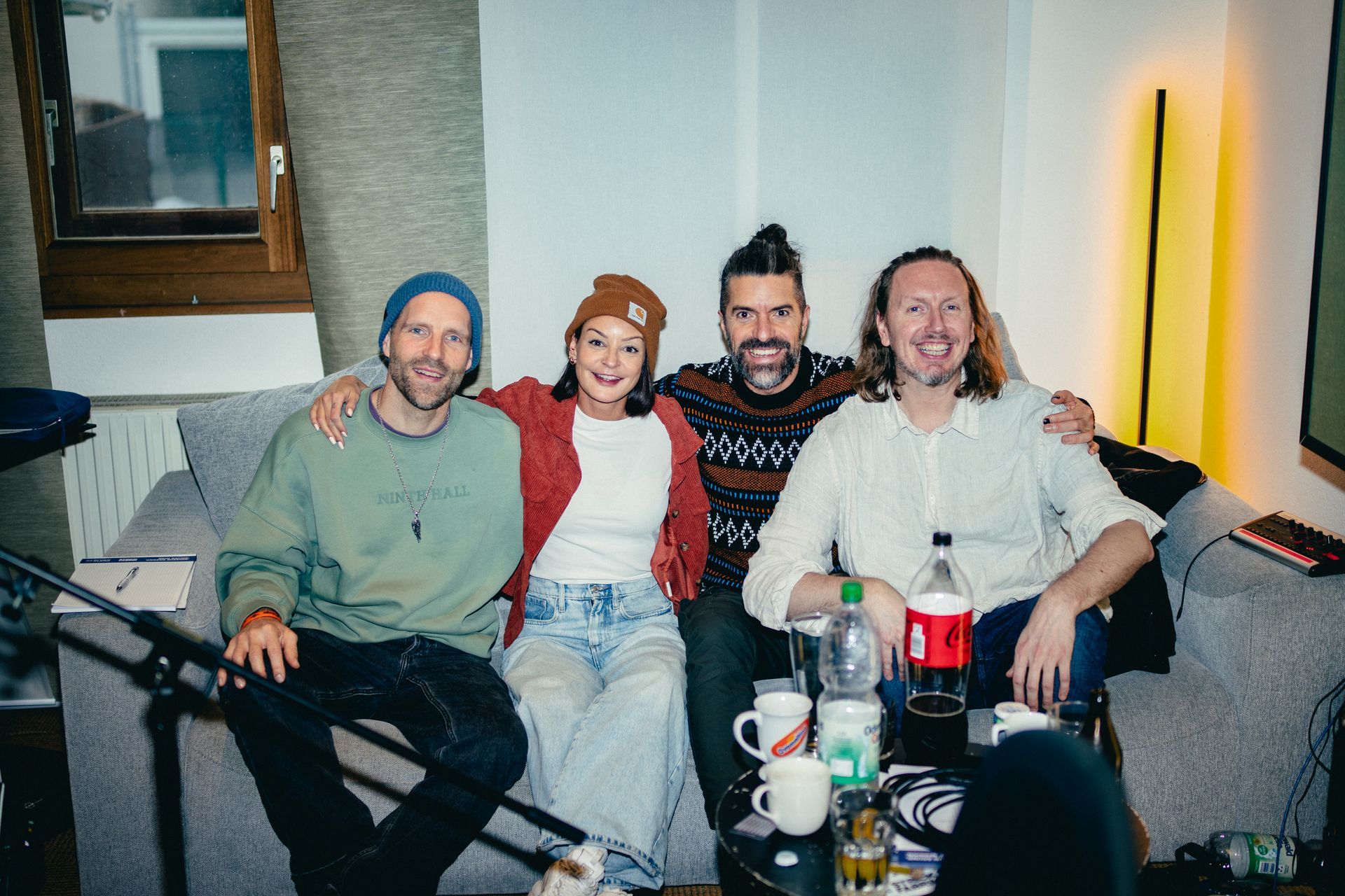 Eine Gruppe der Künstler sitzen auf dem Sofa und lachen.