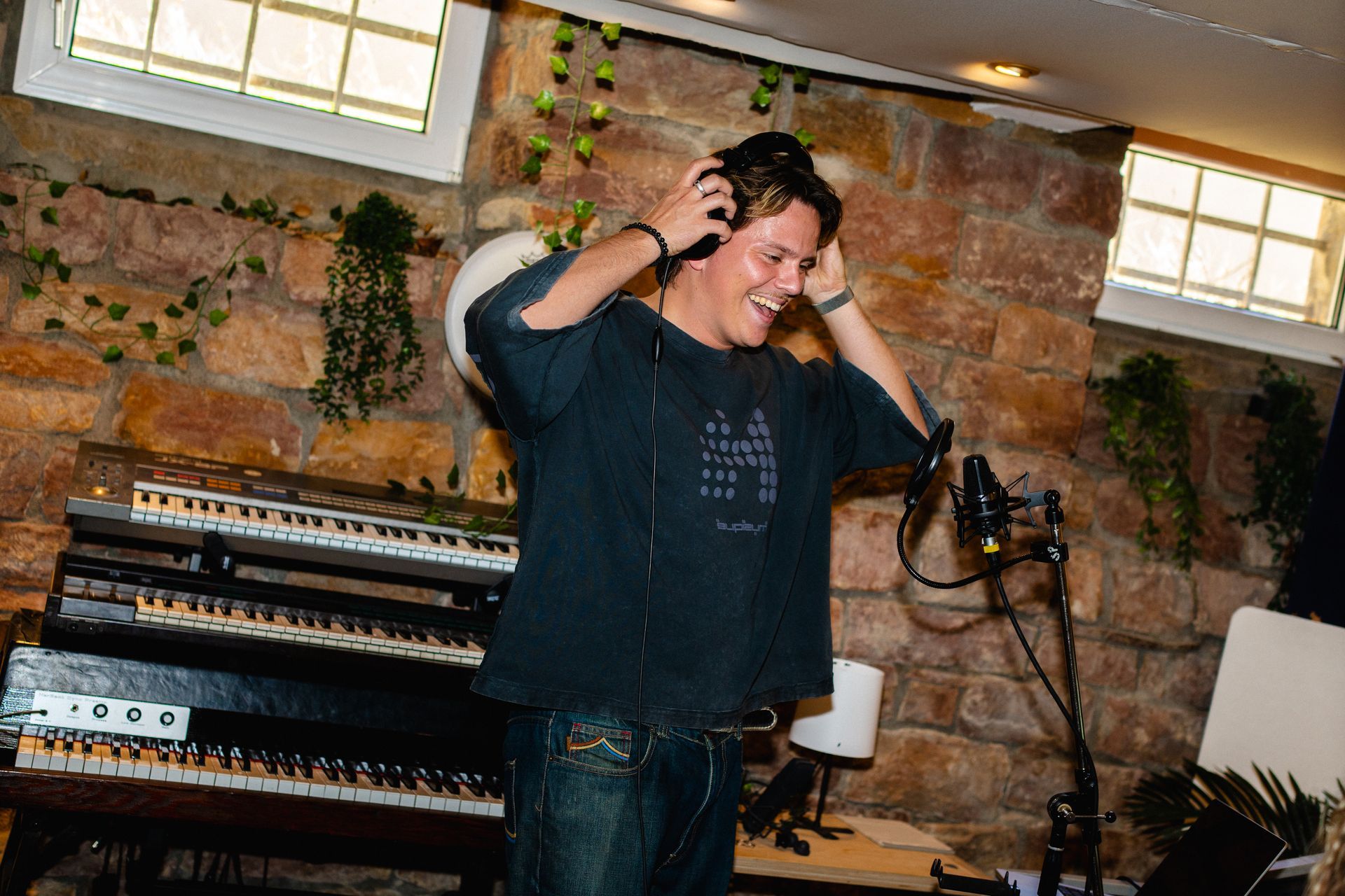 Songcamp Teilnehmer mit Kopfhörern, der lachend auf sein Mikrofon schaut.