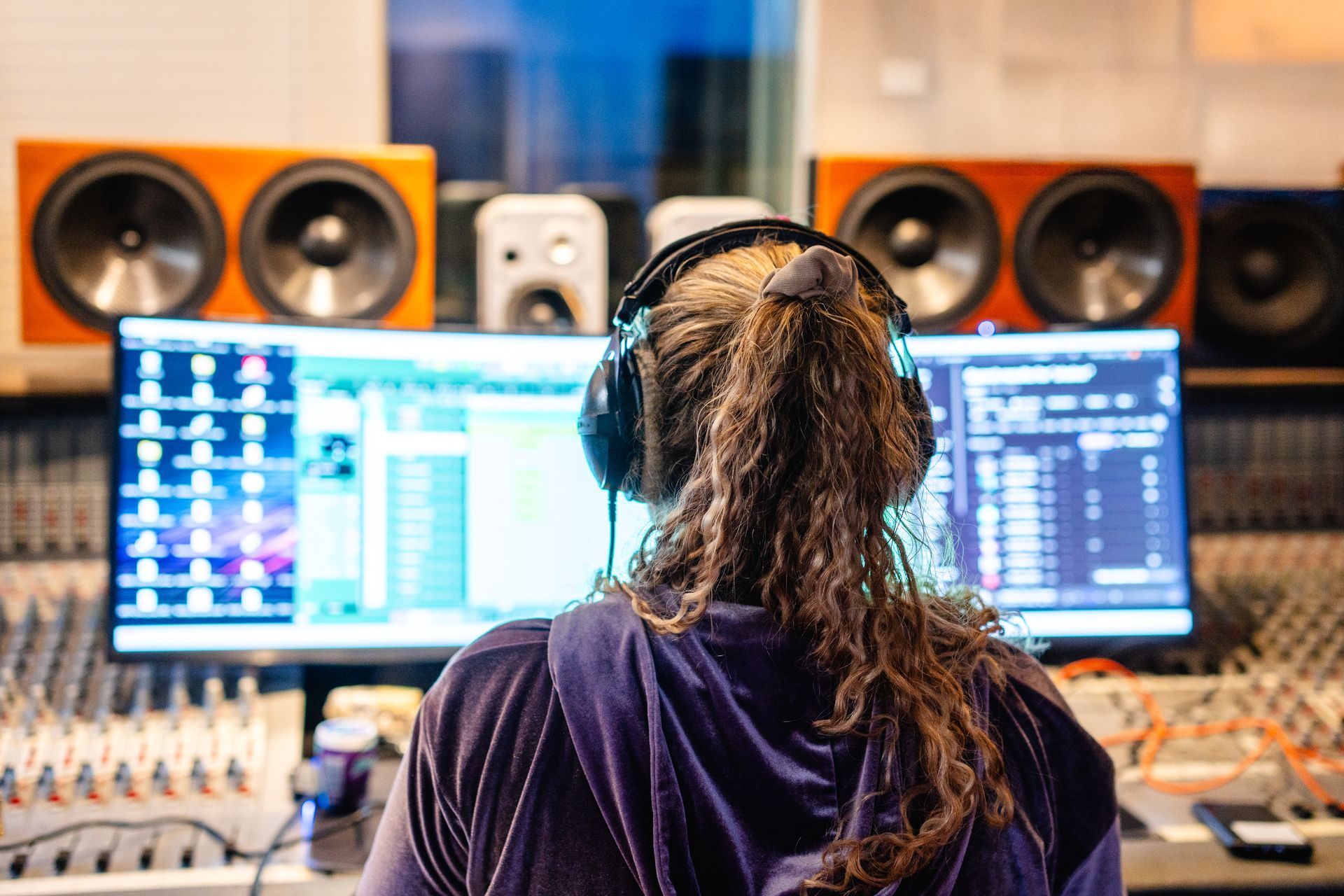 Songcamp Teilnehmerin, die mit Kopfhörern im Studio vor einem PC sitzt.