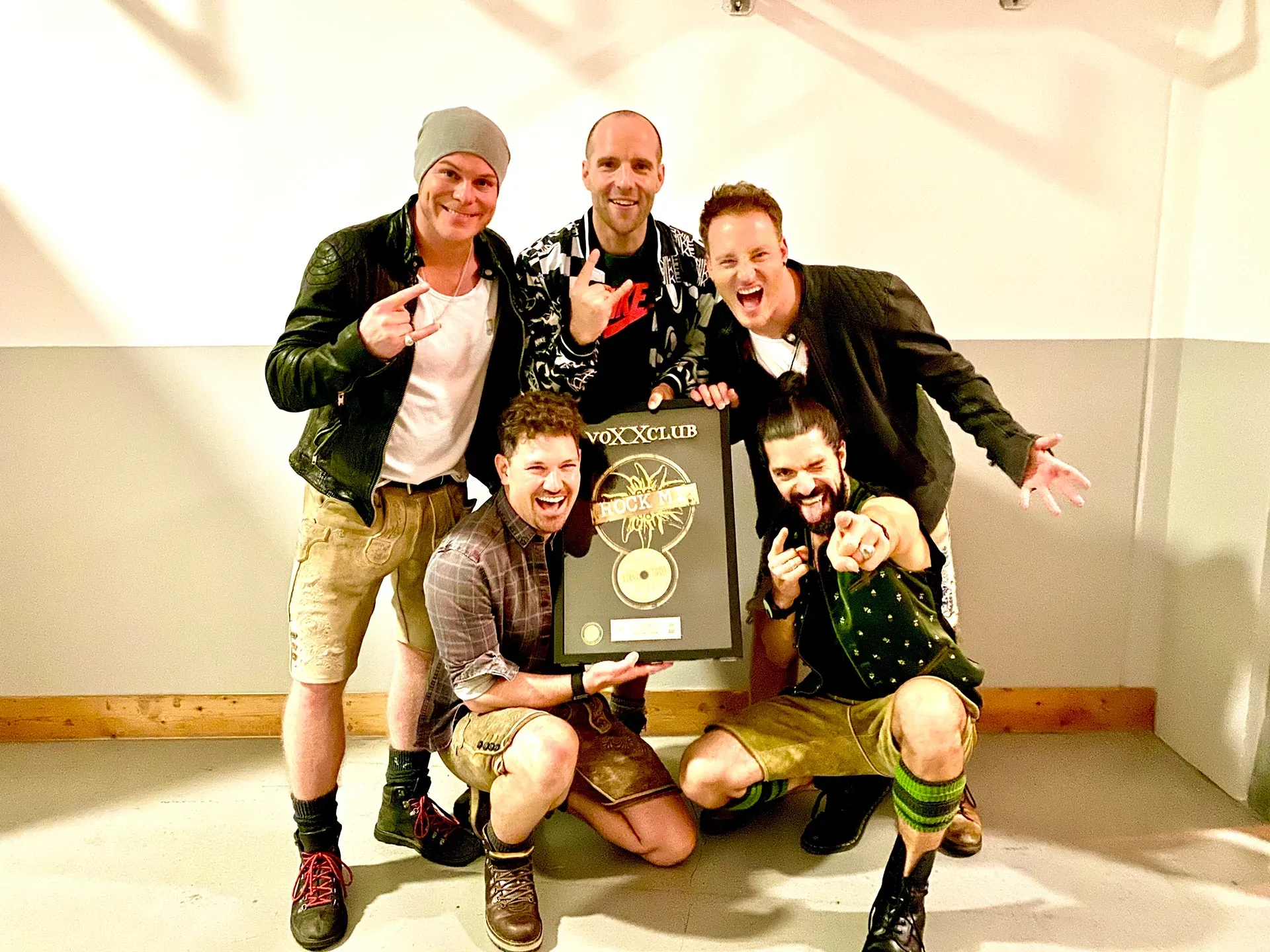 Eine Gruppe von Männern posiert für ein Foto und hält dabei eine goldene Schallplatte in den Händen.