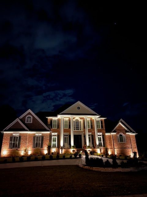 A large brick house is lit up at night.