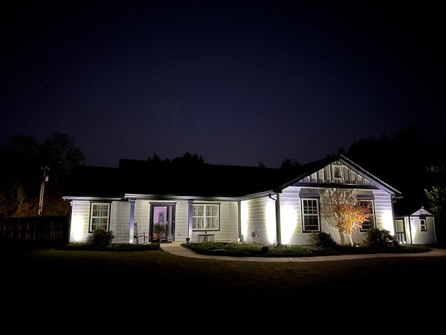 A white house is lit up at night with a dark sky in the background.