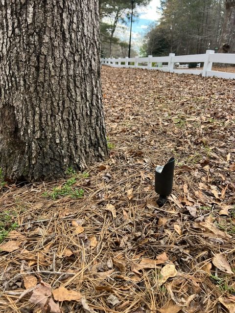 A black light is sitting on the ground next to a tree.