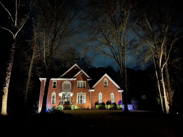A large red brick house is lit up at night