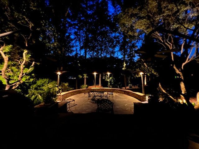 A patio area is lit up at night with trees in the background.