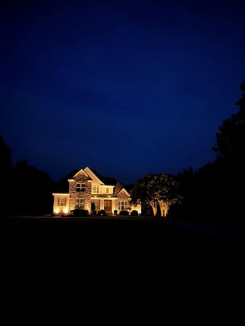 A house is lit up at night with a dark blue sky in the background.