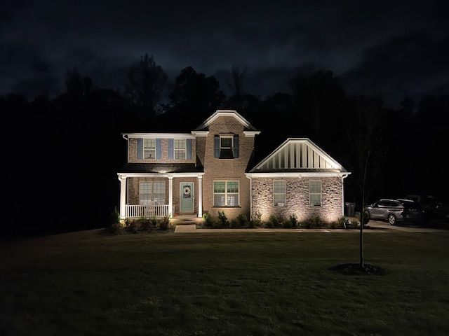 A house is lit up at night with a car parked in front of it.