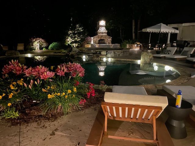 A chair is sitting in front of a swimming pool at night.