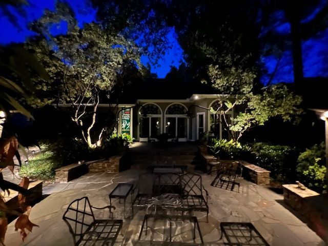 A patio area is lit up at night with trees in the background.