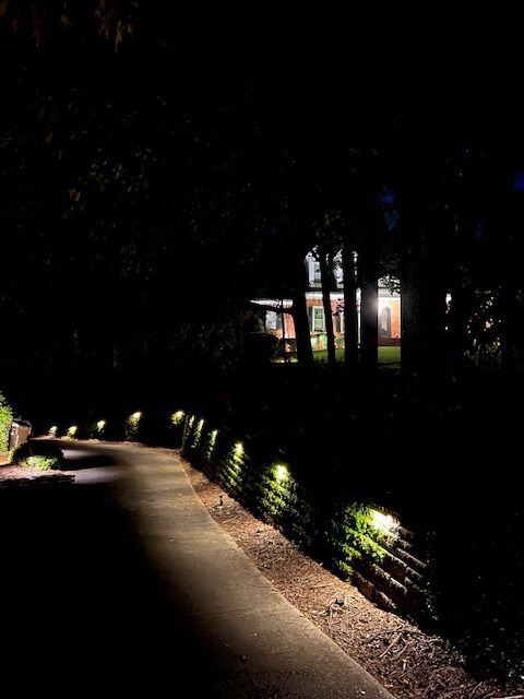 A dark road with lights on the side of it at night.