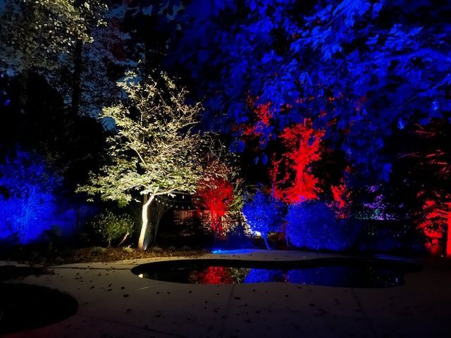 A swimming pool is lit up with red , white and blue lights.