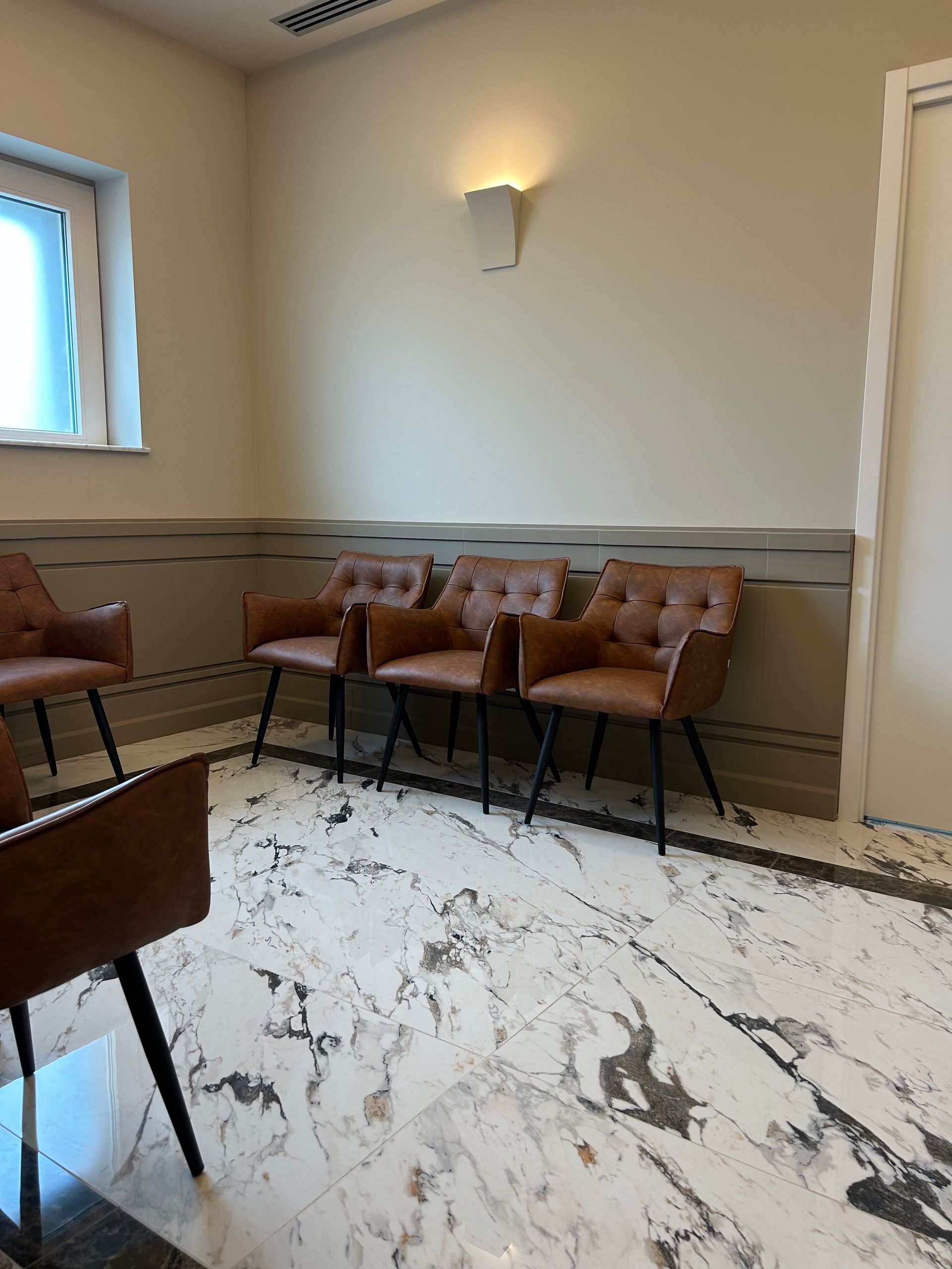 Una sala d'attesa con sedie e pavimento in marmo