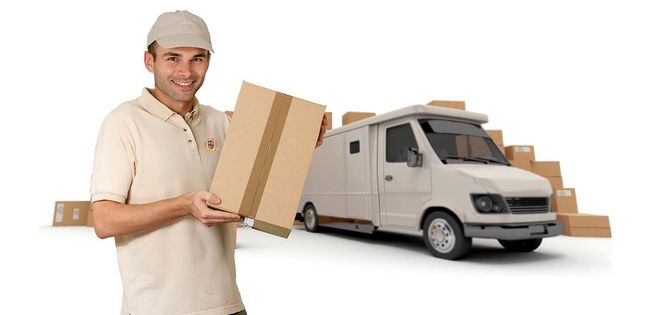 Un repartidor con uniforme de color claro sonríe mientras sostiene una caja de cartón, con una furgoneta de reparto y paquetes cerca.