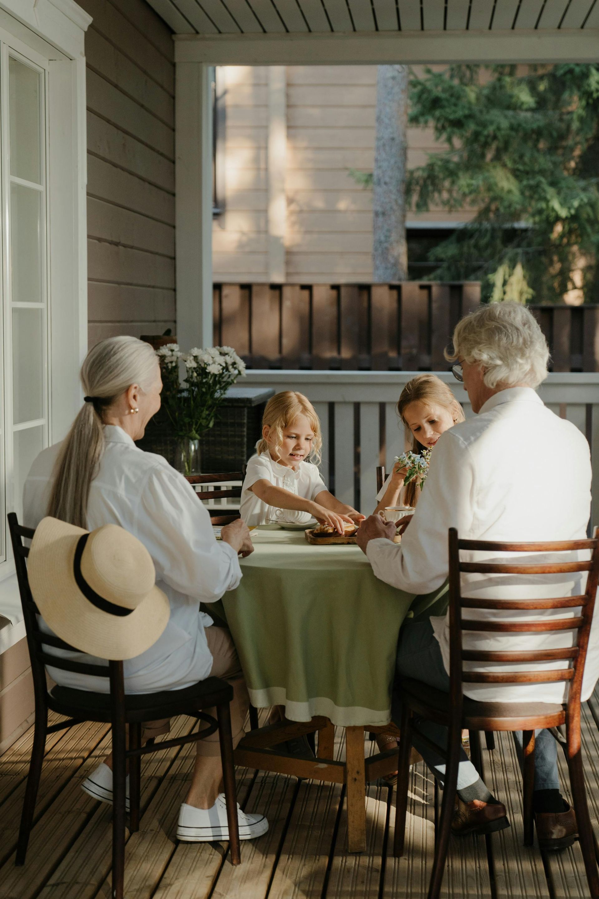 A family is sitting at a table on a porch.