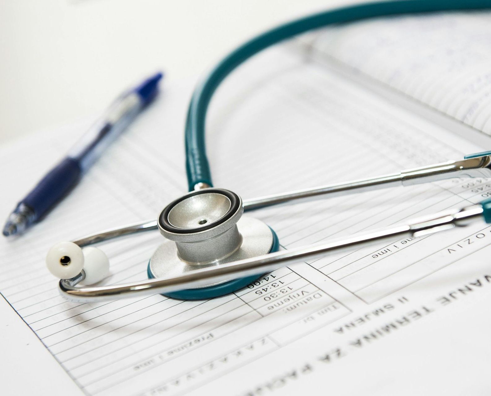 A stethoscope is laying on a piece of paper next to a pen