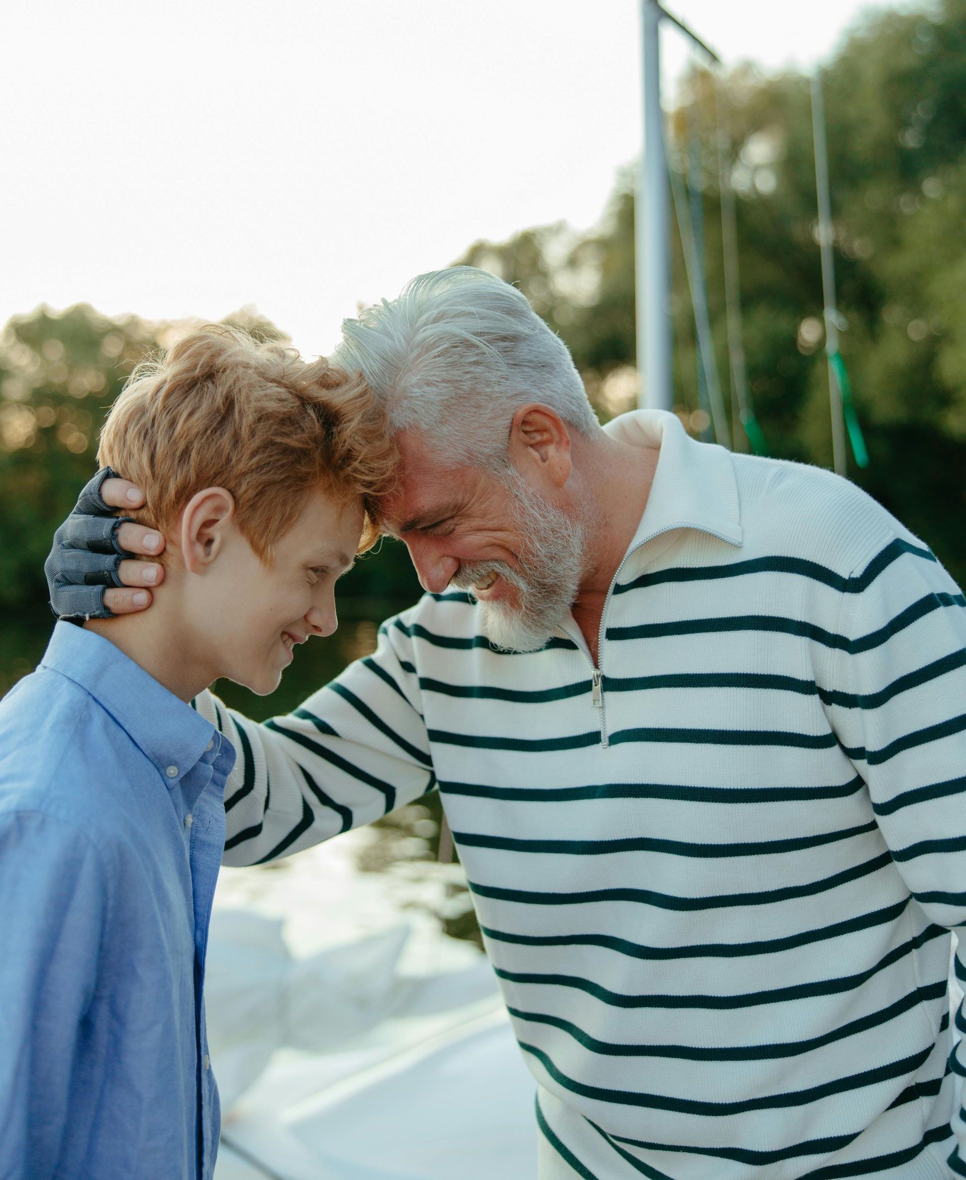 A man in a striped shirt is hugging a young boy on a boat.