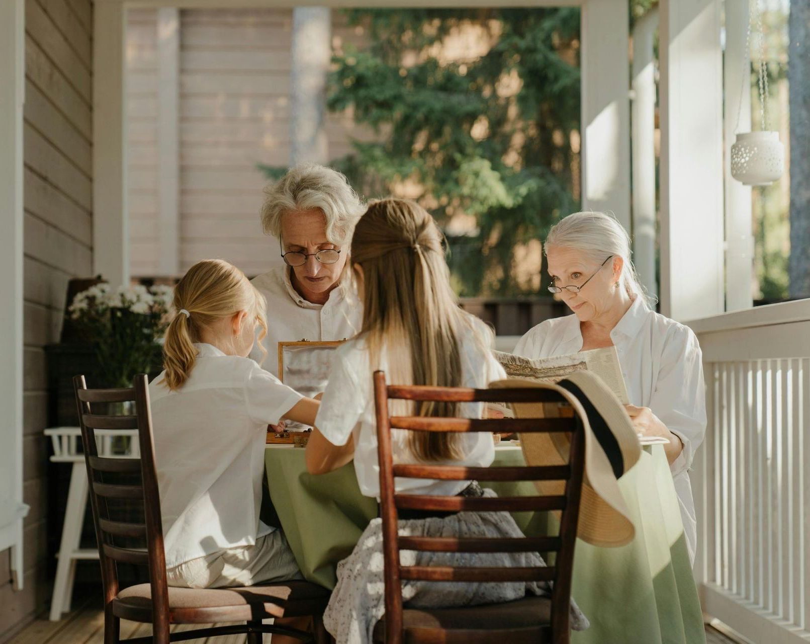 A group of people are sitting around a table on a porch.