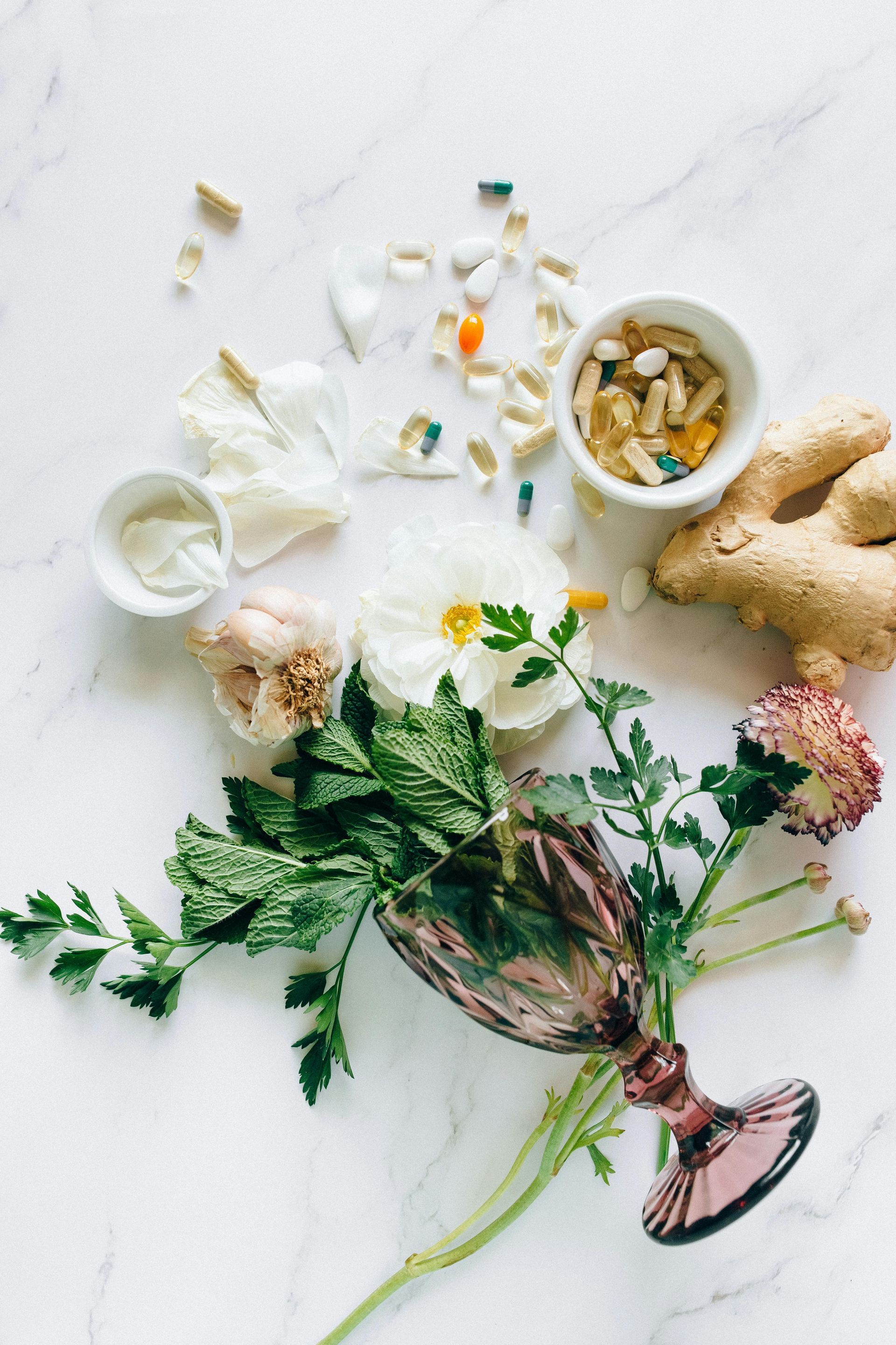 A bouquet of flowers , ginger , and pills on a table.