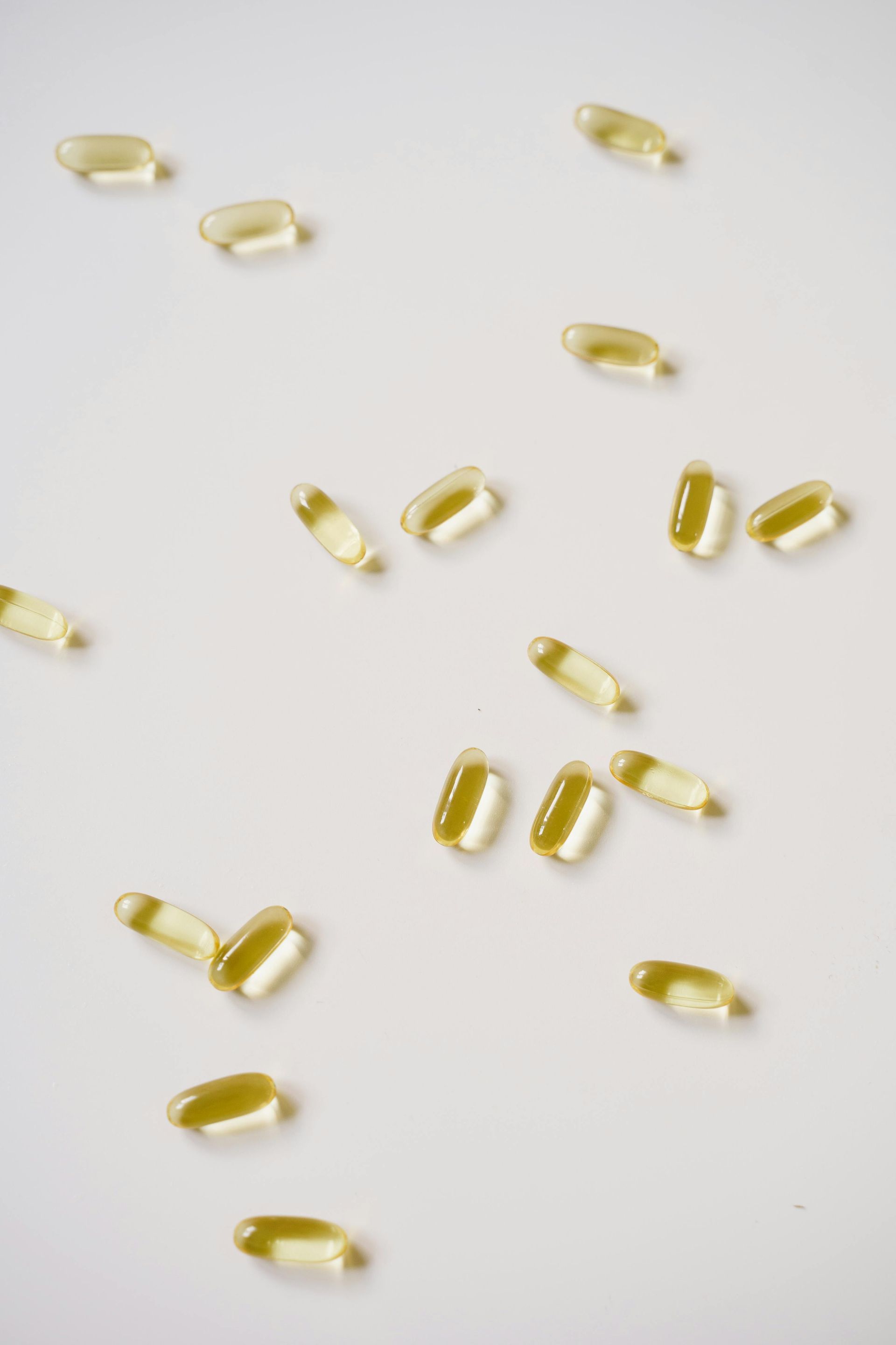 A bunch of yellow pills are scattered on a white surface.