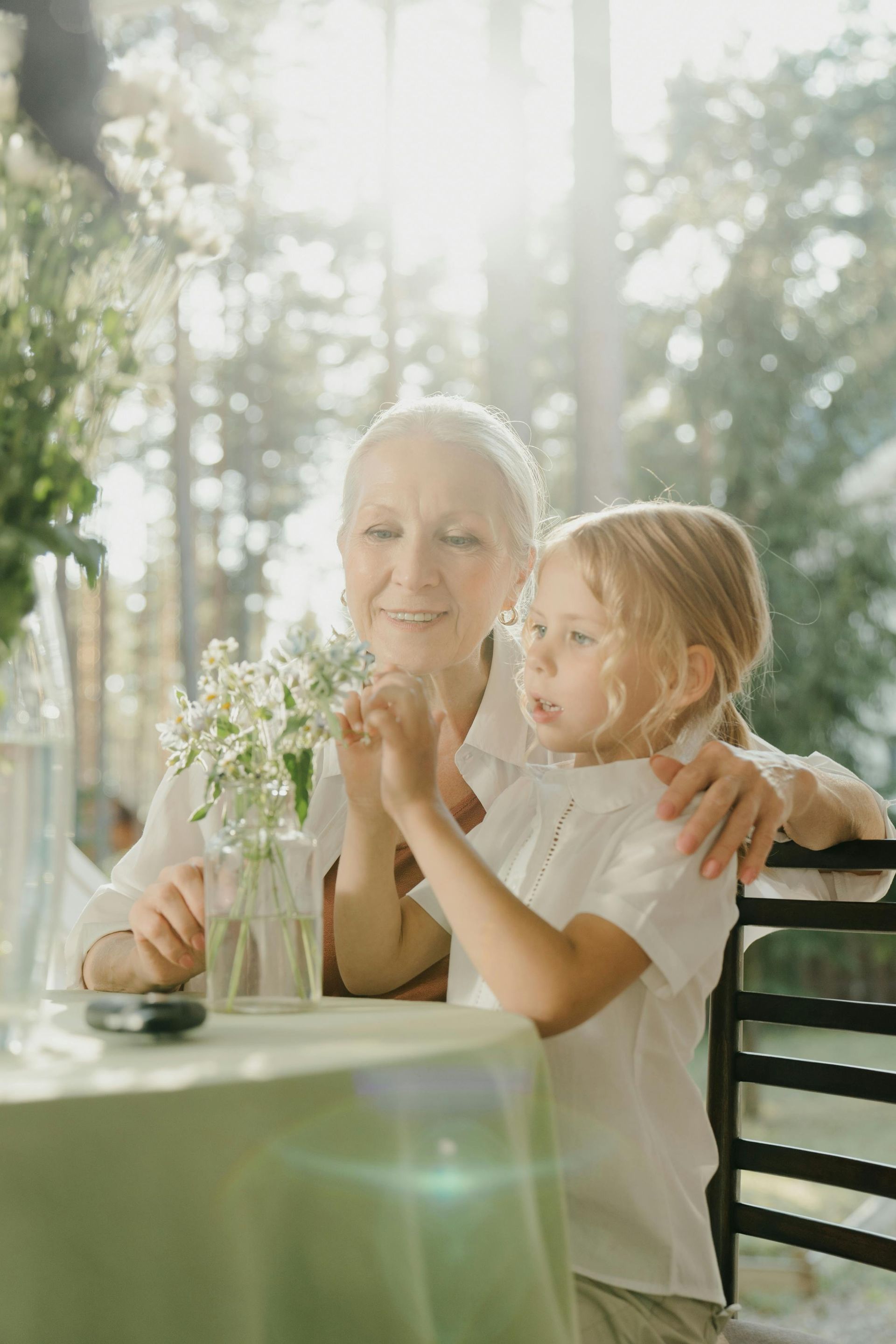 An elderly woman is sitting at a table with a little girl.