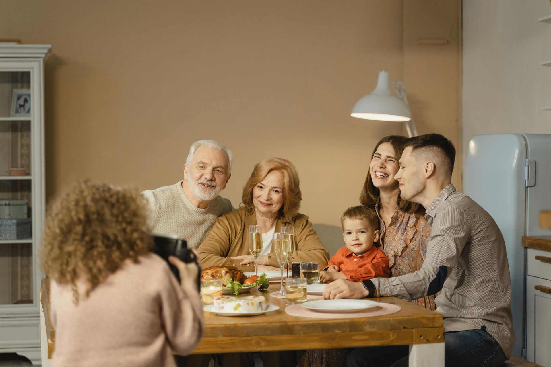 A woman is taking a picture of a family sitting at a table.