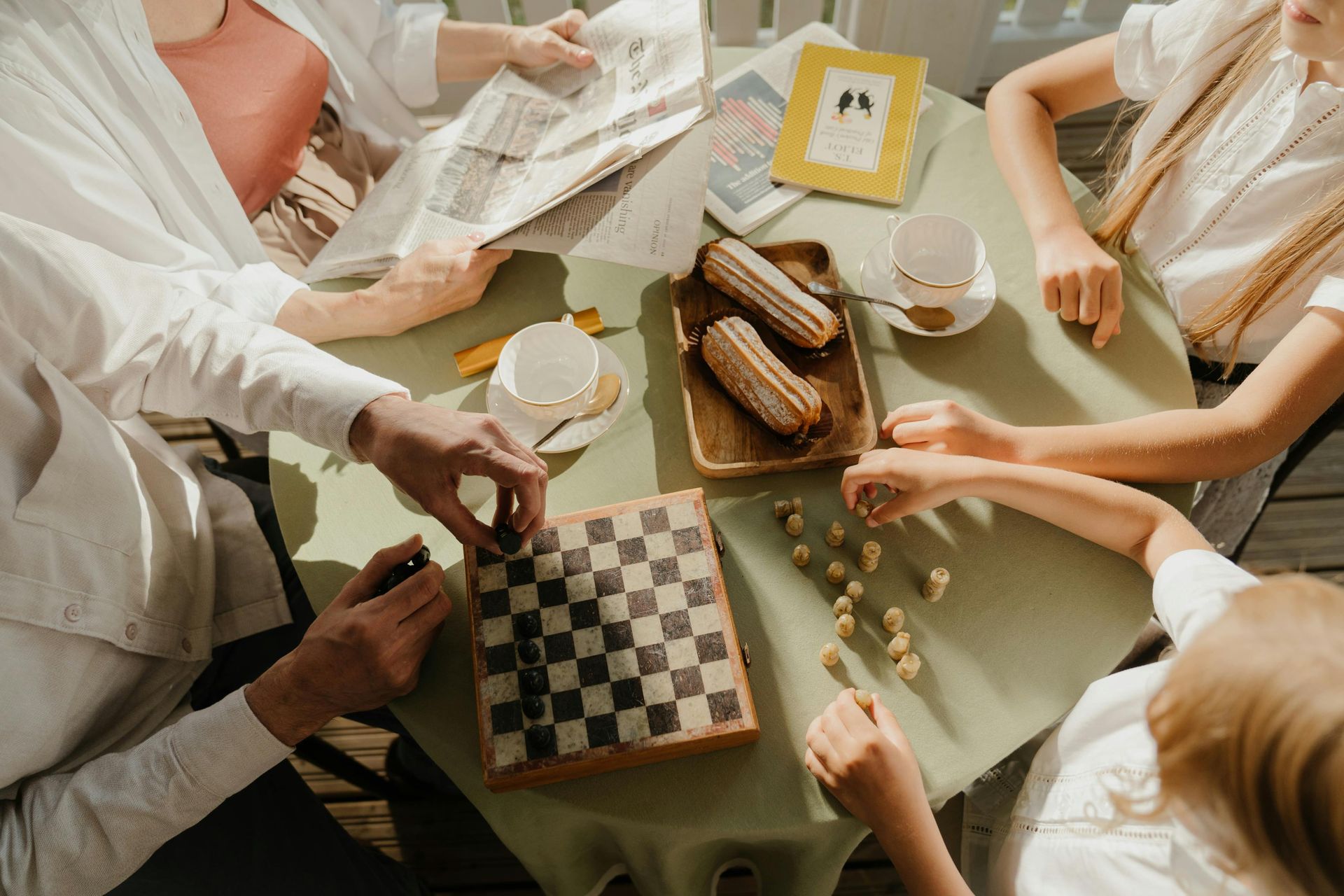 A group of people are sitting around a table playing chess.