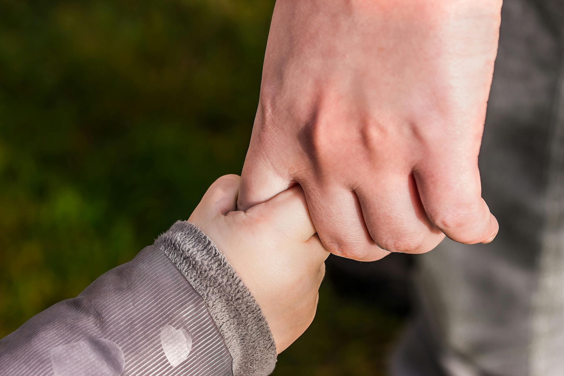 A little girl is holding a man 's hand.
