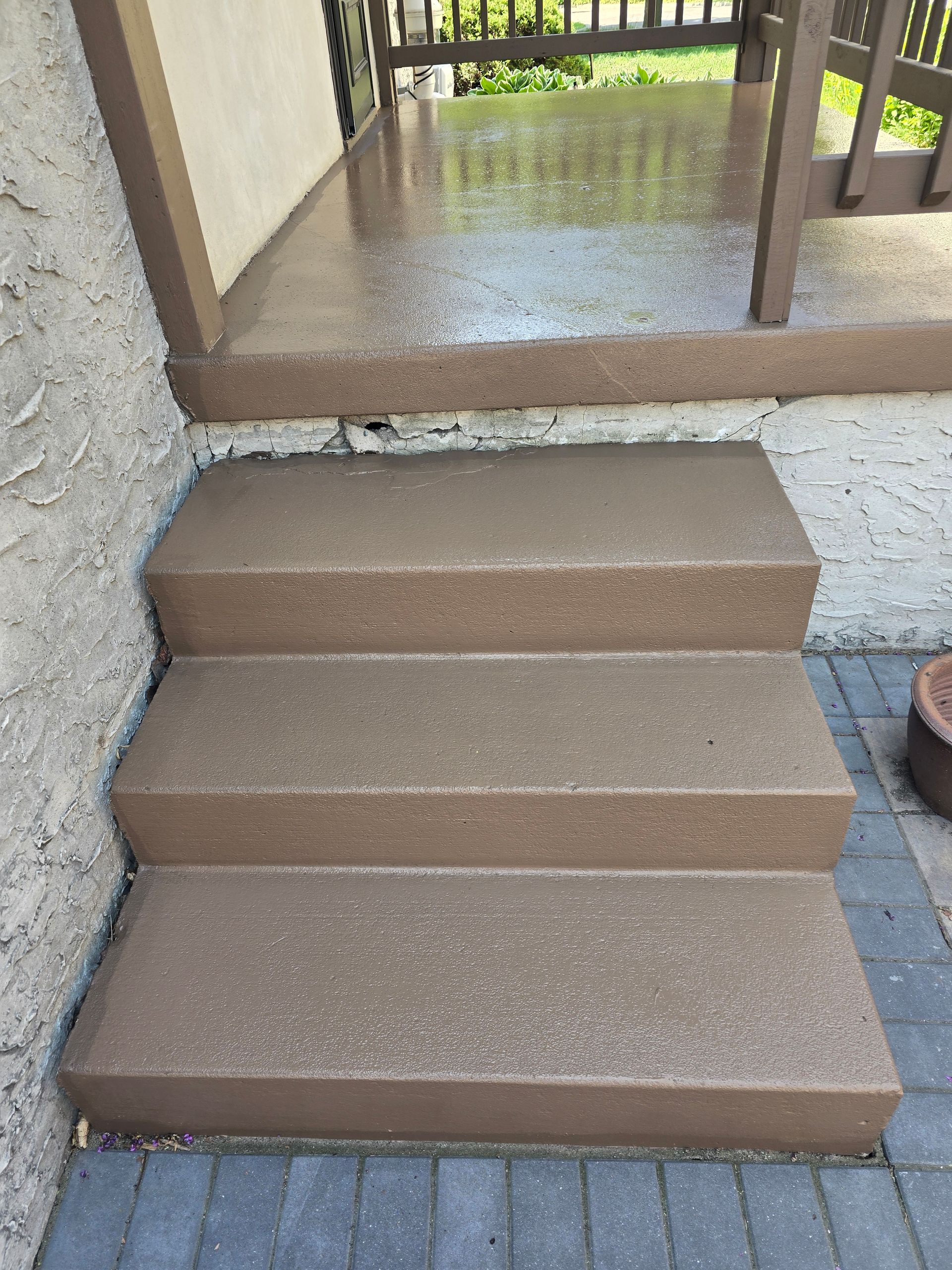 A set of stairs leading up to a porch with a chair on it.