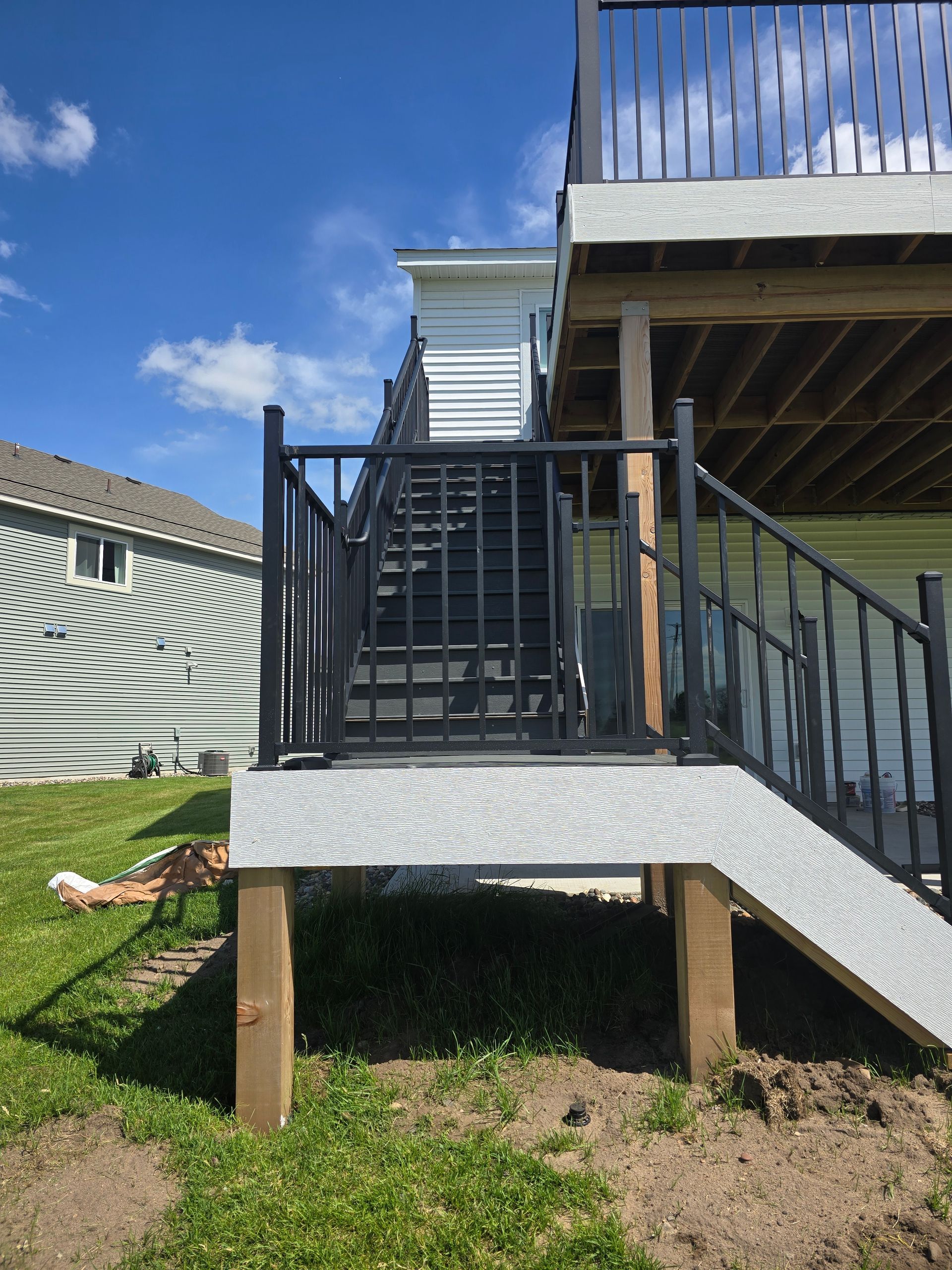 A deck with stairs leading up to it and a house in the background.