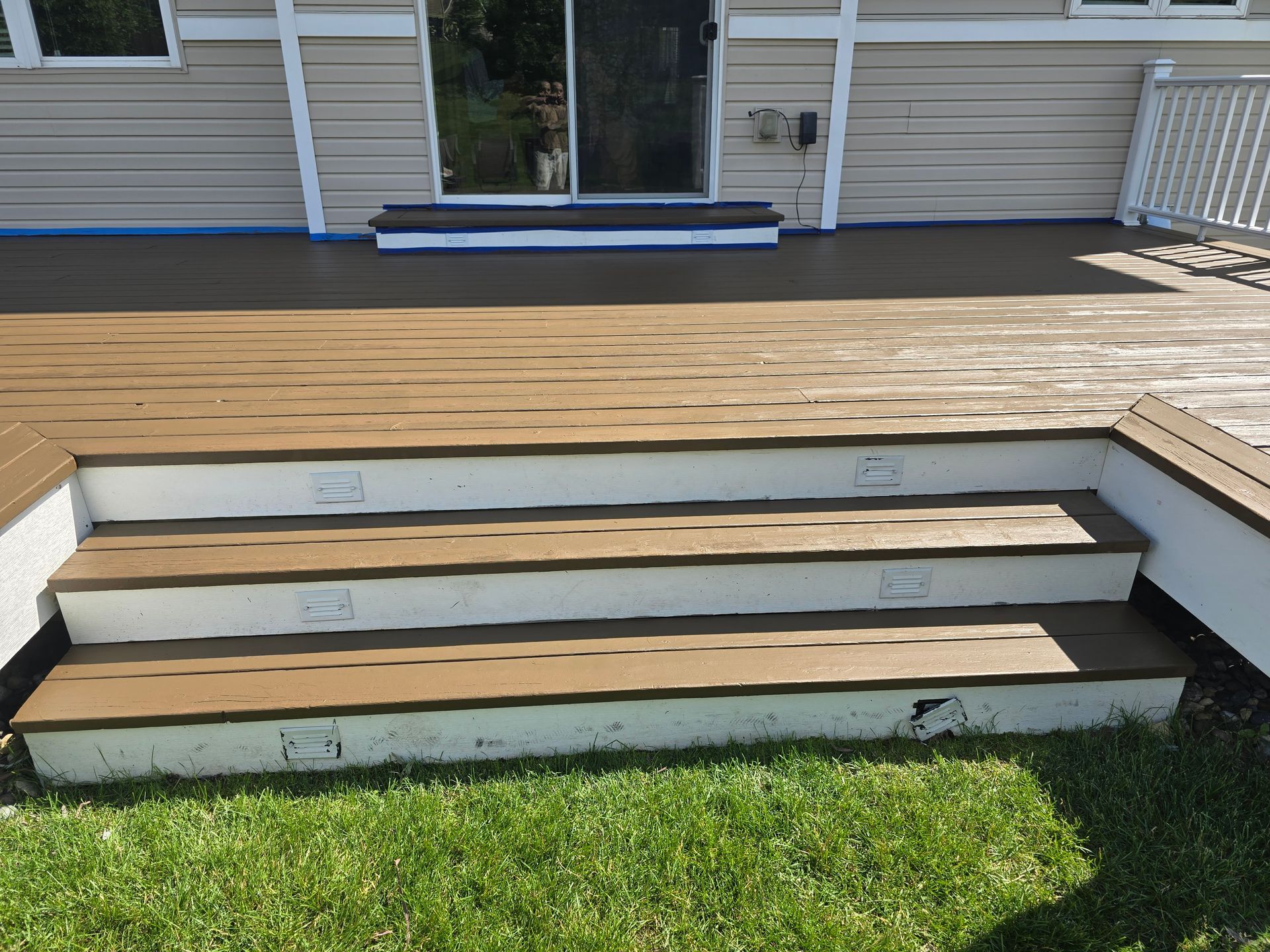 A wooden deck with stairs leading up to it in front of a house.