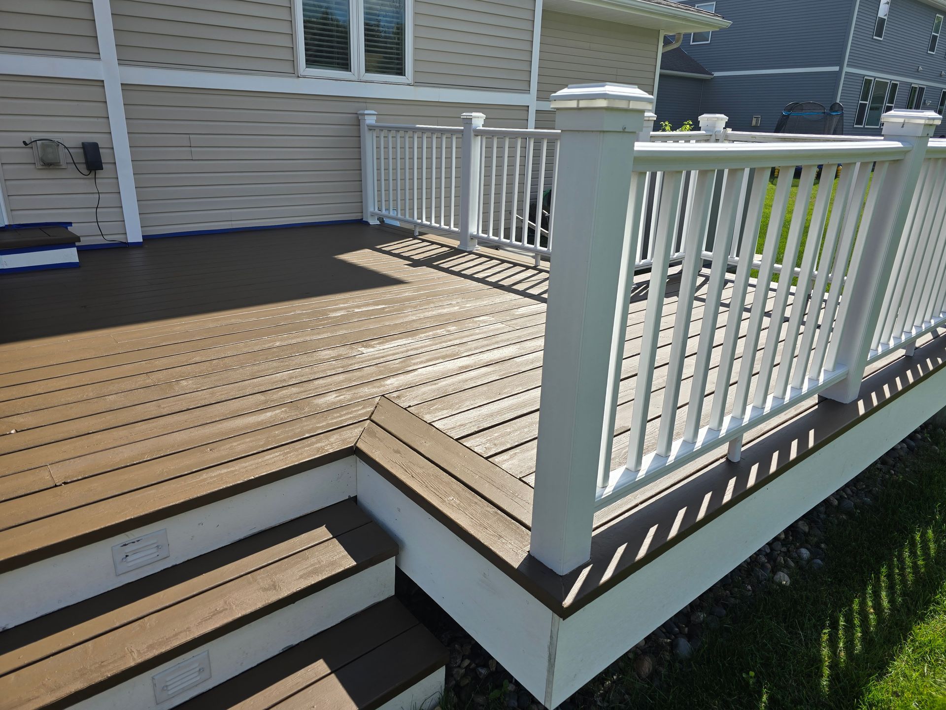 A wooden deck with stairs and a white railing